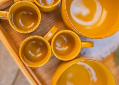 Top-down view of vibrant yellow ceramic cups and bowls on a wooden tray, showcasing an inviting setup.