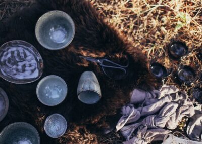 Overhead of composition with ceramic and glass utensil near scissors placed on fur on dry grass on sunny day